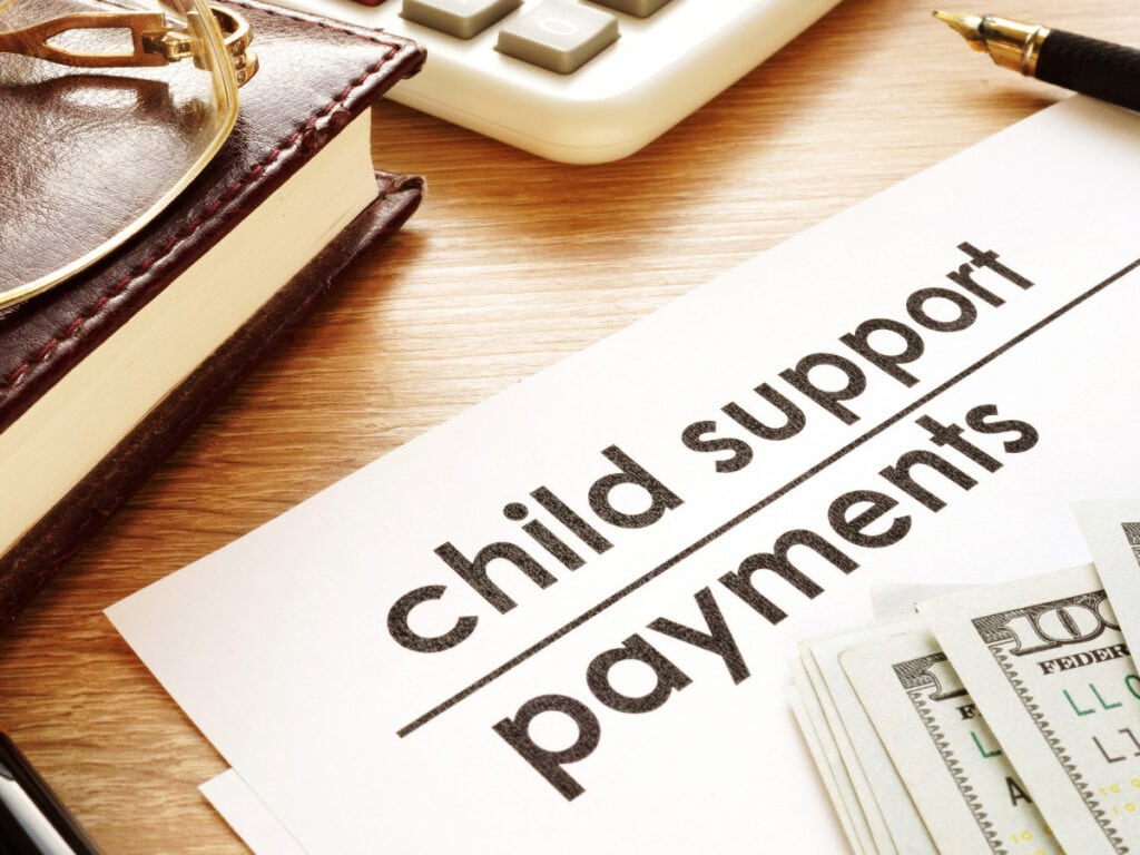 Pozew o alimenty Katowice – przygotowanie dokumentów: notatnik z napisem „child support payments”, długopis i okulary, kompletowanie dowodów do sądu.